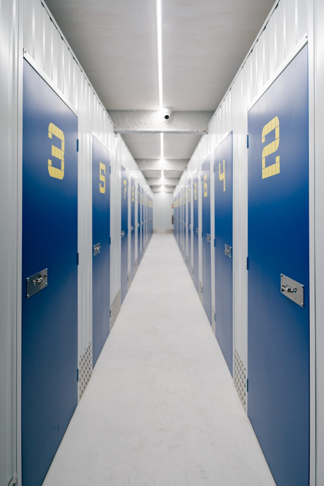 Pasillo de trasteros con puertas azules y números amarillos